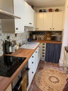 a kitchen with white cabinets and a wooden counter top at Charming townhouse in Bruton in Bruton