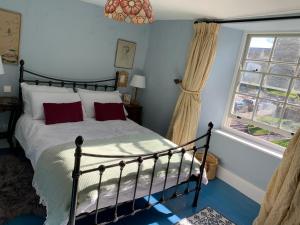 a bedroom with a bed with red pillows and a window at Charming townhouse in Bruton in Bruton