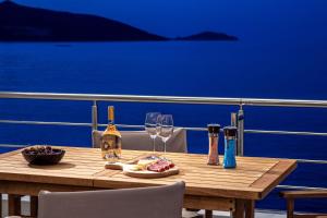 a wooden table with wine bottles and glasses on a boat at La Vista Apartment in Agios Nikolaos