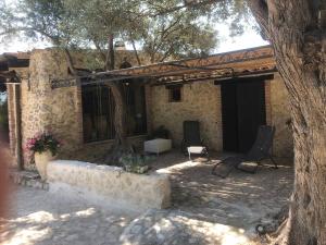 una casa de piedra con 2 sillas y un árbol en Roba Degli Ulivi, en Agrigento