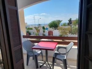 a red table and chairs on a balcony at Appart Gyptis Résidence Chahrazad in Sfax