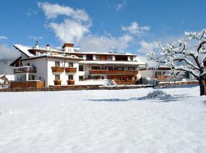 a house in the snow with a snow covered yard at Hotel Alp Cron Moarhof in Valdaora