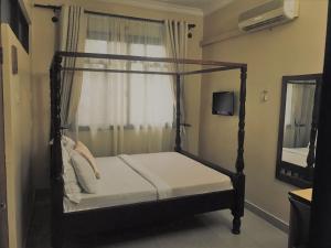 a bedroom with a canopy bed with a window at Transit Airport B&B in Dar es Salaam