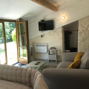 a living room with a couch and a tv on the wall at Le Petit Appartement `a Cariad La Rebeuse in Corgnac-sur-lʼIsle