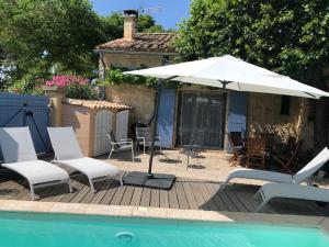 a patio with chairs and an umbrella next to a pool at Maison de plain pied pour 4 pers piscine Lussan in Lussan