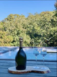 a bottle of wine and two wine glasses on a table at F2 avec jacuzzi, pétanque, à 3 min mer, dans grande propriété in Porticcio