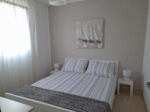 a bed in a white room with a window at Apartmani HERMES Jadrija in Šibenik