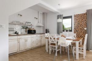 a kitchen with a wooden table and white chairs at APARTAMENT8 Wellness Sauna View 5os in Szczyrk