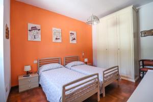 two beds in a bedroom with an orange wall at Margherita Guest House in Coreglia Ligure