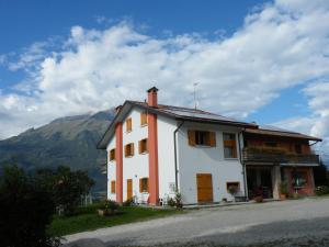 a white and orange house with a mountain in the background at Agriturismo Al Bachero in Belluno