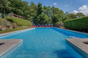 a blue swimming pool with red chairs and trees at CASA PAZOS-ARBO in Arbo