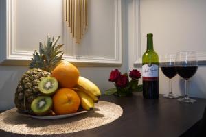 Jacuzzi Spa Black Apartment في كراكوف: وعاء من الفواكه على طاولة مع زجاجة من النبيذ