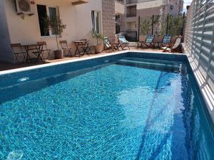 uma grande piscina azul com cadeiras e mesas em Sun and Sea Apartments em Budva