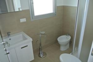 a bathroom with a sink and a toilet and a window at Condominio Shedir in Bibione