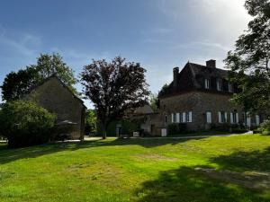 ein altes Backsteinhaus mit einem Rasenhof in der Unterkunft La maison du Gardien - LE PRIEURÉ DU PREUX 
