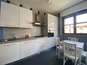 a kitchen with white cabinets and a table with chairs at Chicco family - Appartamento spazioso per famiglie e soggiorni business - Cinelli Apartment in Vercelli