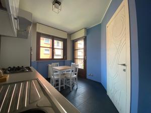 a kitchen with blue walls and a table and a door at Chicco family - Appartamento spazioso per famiglie e soggiorni business - Cinelli Apartment in Vercelli +27 photos