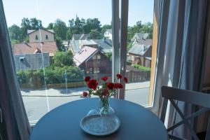 a vase of flowers on a table in front of a window at Plytu 9 apartment in Palanga