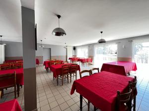 a dining room with red tables and chairs at Contact Hotel Les Montois in Céaux