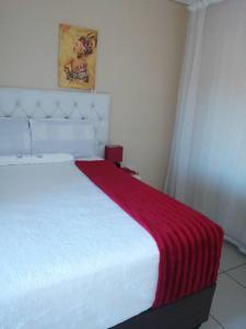 a bedroom with a white bed with a red blanket on it at Beautiful Gate Guesthouse in Palatswe