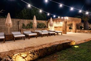 un patio con panche e luci di notte di Villa con Piscina by Corallo Blu Salento a Taviano