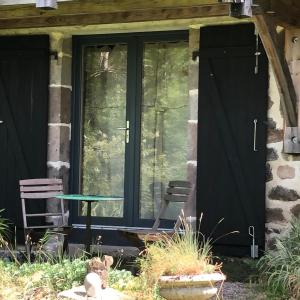 uma porta de vidro de uma casa com uma cadeira e uma mesa em au rocher de Combières em Mandailles