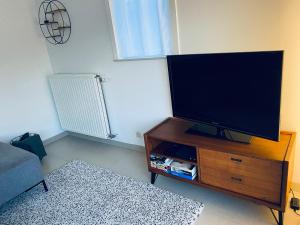 ein Wohnzimmer mit einem Flachbild-TV auf einem hölzernen Entertainment-Center in der Unterkunft Westerhuisje in Middelkerke