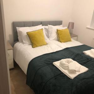 ein Bett mit zwei gelben Kissen und einem Hut darauf in der Unterkunft Lovely 3-Bed House in Chafford Hundred in North Stifford