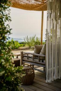 eine Holzveranda mit einer Bank und einem Sonnenschirm in der Unterkunft Terre de Maquis, maison d'hôtes vue mer Corse in Sari-dʼOrcino