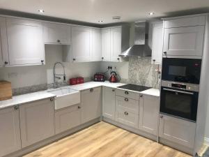 een keuken met witte kasten en een wastafel bij Heart of Henley 1 & 2 Bedroom Apartments in Henley on Thames