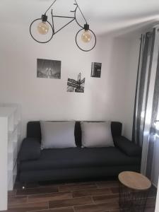 ein Wohnzimmer mit einem schwarzen Sofa und 2 Leuchten in der Unterkunft Studio apartman Noa in Rijeka