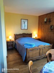 um quarto com uma grande cama de madeira com lençóis azuis em Chambre La Lavandula Col de Turini 