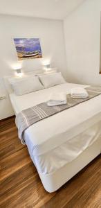 2 letti in una camera con pareti bianche e pavimenti in legno di Bella Lucia a Portoroz