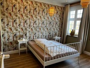 Schlafzimmer mit einem Bett mit Blumentapete in der Unterkunft Gästehof Cafe im Schafstall in Barsinghausen