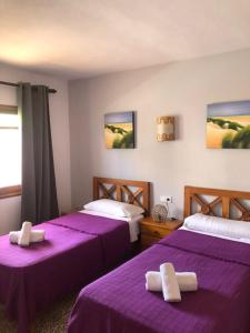 two beds in a room with purple sheets at Apartamentos Colomar in Es Figueral Beach