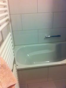 a bath tub in a bathroom with a white wall at Gästezimmer in Zurich