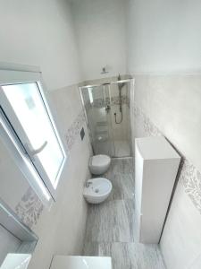 a white bathroom with a shower and a toilet at La perla del mare in La Caletta