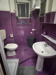 un bagno viola con lavandino e servizi igienici di Cuore Di Napoli a Napoli