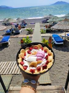 a person holding a bowl of food on a beach at Yücel Hotel in Fethiye