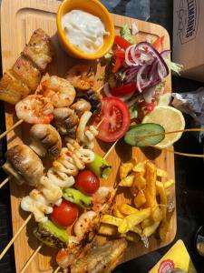 a wooden cutting board with shrimp and vegetables and dipping sauce at Yücel Hotel in Fethiye