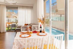 - une salle à manger avec une table, des chaises et une piscine dans l'établissement Luxurious villa with children's area (5 min to the sea), à La Horadada