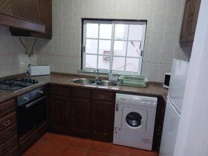 uma cozinha com um lavatório e uma máquina de lavar roupa em Gota D'agua Guest House em Vila Nova de Milfontes