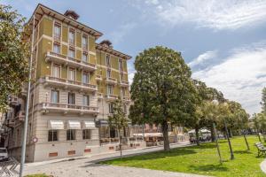 韦尔巴尼亚Hotel Pallanza by LVG Hotel Collection的一座黄色的大建筑,前面有树木