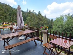 a woman sitting at a table on a deck with an umbrella at Chambre La Lavandula Col de Turini in Granges de Faisset
