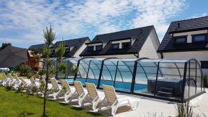 Osada Wypoczynku Jantar Resort&Spa - Luksusowe Domki z Basenem, Sauną i Jacuzzi في يانتار: صف كراسي للجلوس بجانب مسبح