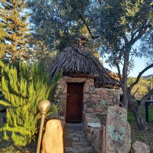 a small stone building with a grass roof at Munduge b&b in Lotzorai