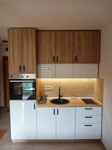 uma cozinha com armários brancos e um lavatório em Studio apartman Gorski kristal em Zlatibor