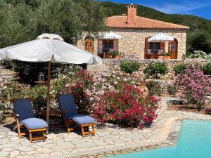 - une terrasse avec 2 chaises et un parasol à côté de la piscine dans l'établissement Boutique apart-hotel Galini, member of the best small hotels in Greece, Adults only, à Volímai