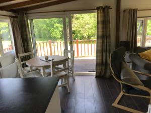 Pheasant Lodge في بيلث ويلز: غرفة معيشة مع طاولة وكراسي وشرفة