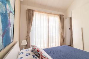 sypialnia z niebieskim łóżkiem i oknem w obiekcie Suite Frida Rimini w Rimini